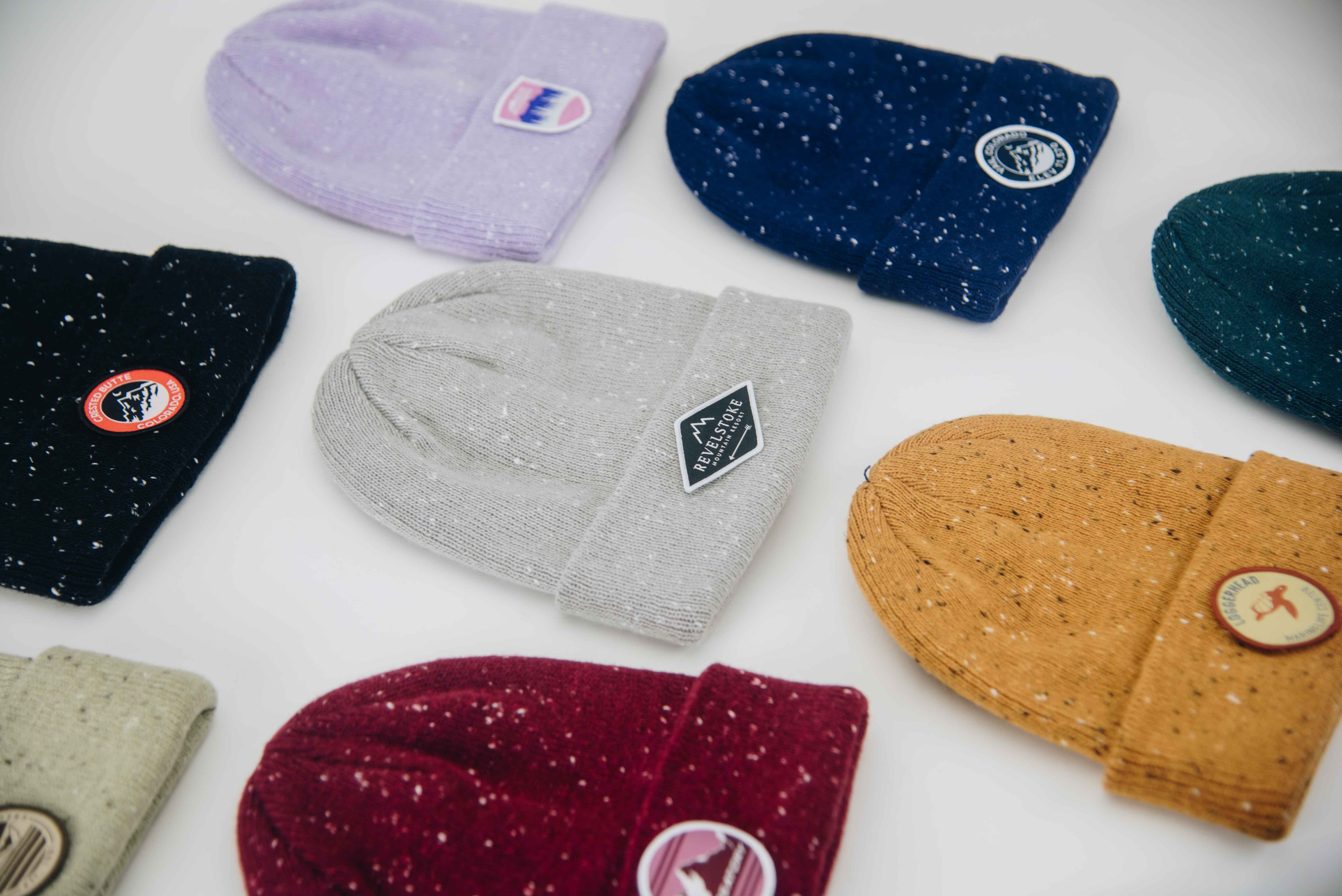 Collection of colorful beanies and mittens with visible brand logos on a white background