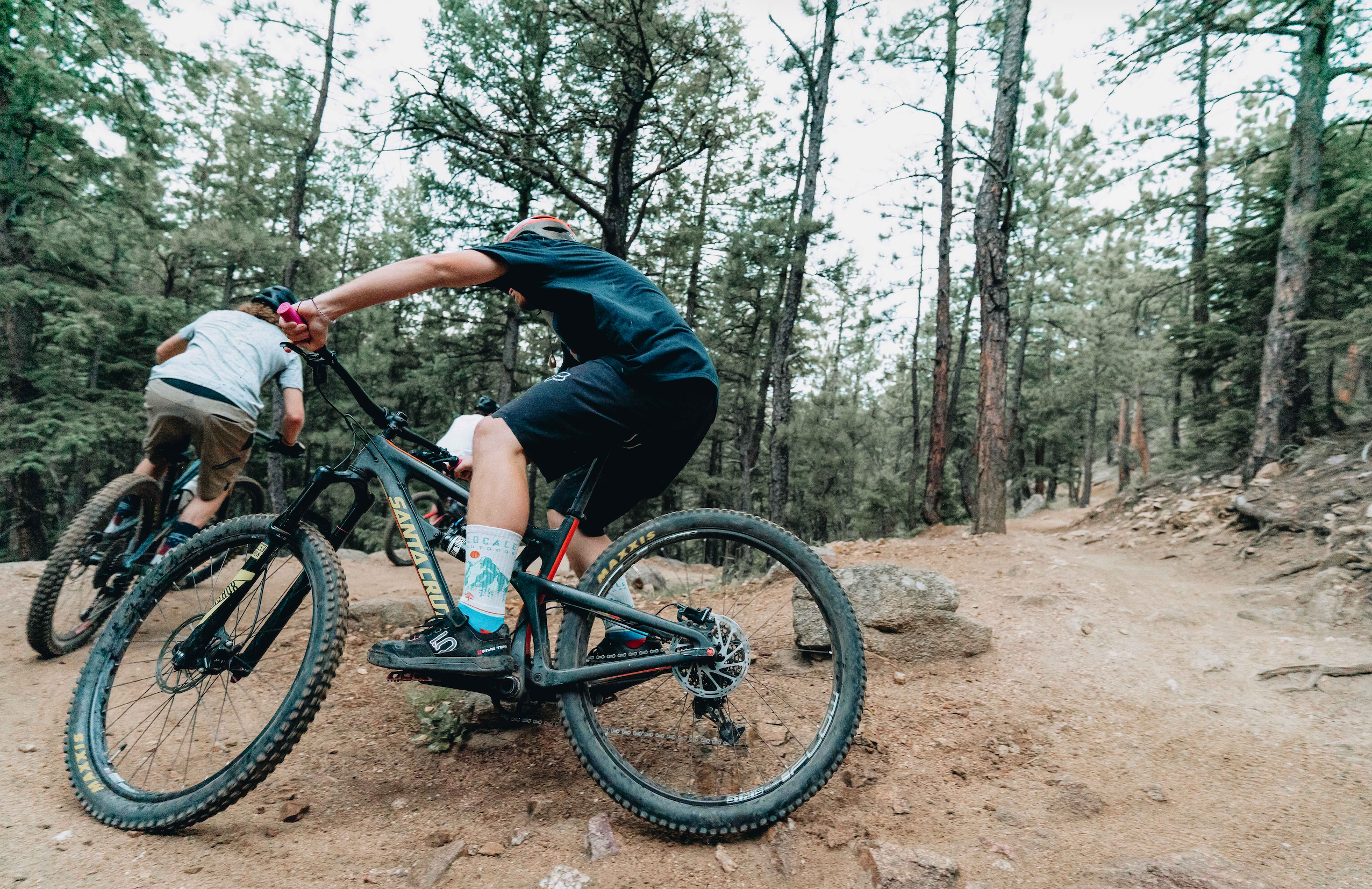 Two people riding mountain bikes on a trail in a forest