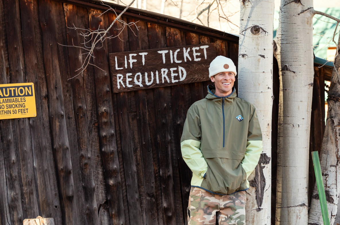 Person standing in front of a wooden building with a 'Lift Ticket Required' sign.